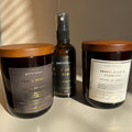 Three petrichor products including a candle, a spray, and a candle on a neutral background