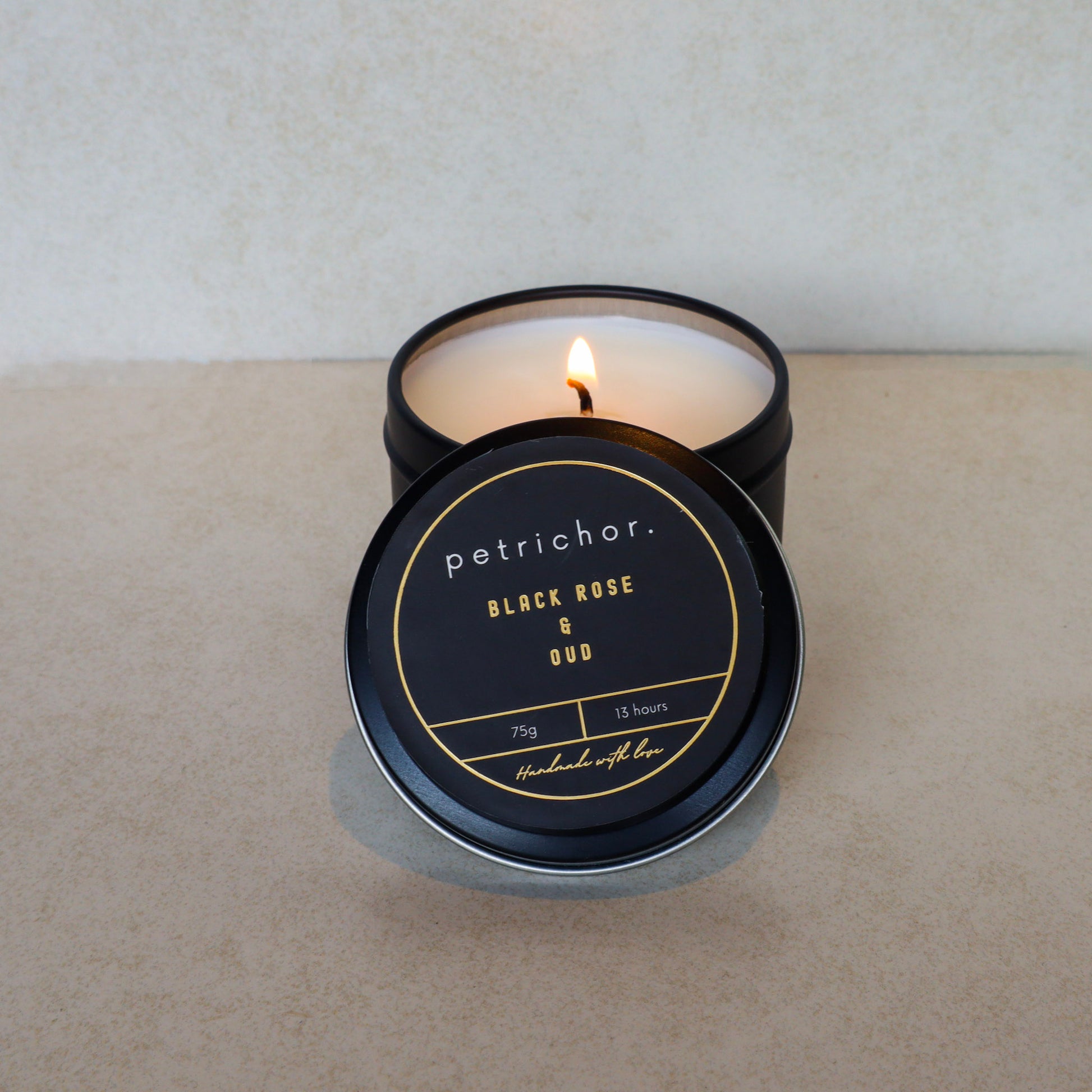 Petrichor candle with black lid on a light surface