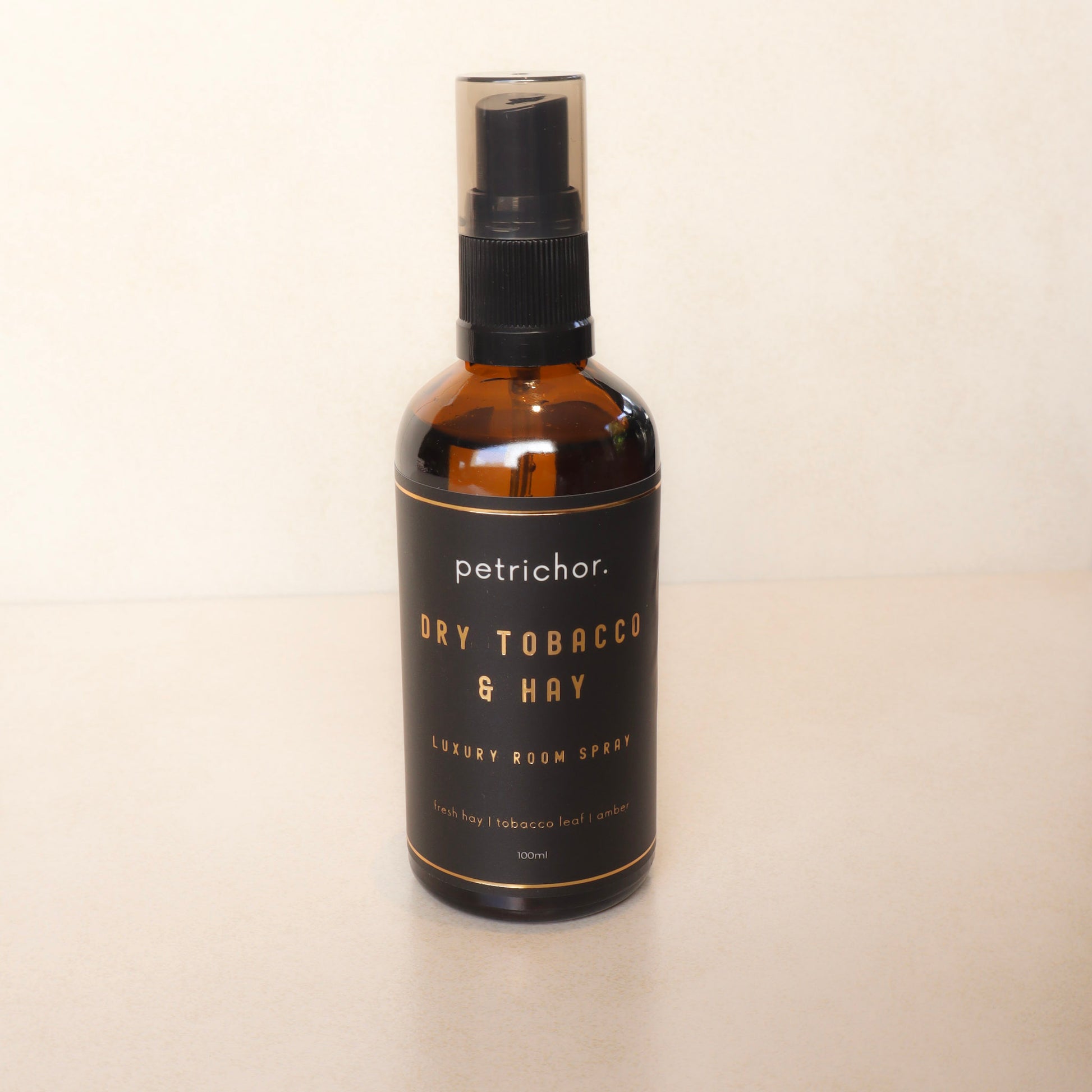Bottle of petrichor Dry Tobacco & Hay room spray on a beige background