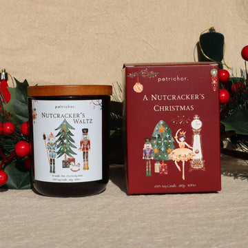 Nutcracker's Waltz Christmas soy candle with oak lid beside its A Nutcracker's Christmas gift box