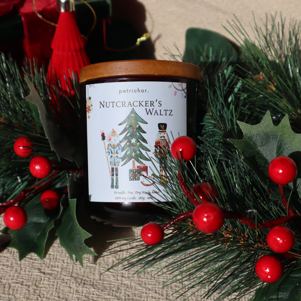 Nutcracker's Waltz Christmas soy candle on a pine wreath with red berries