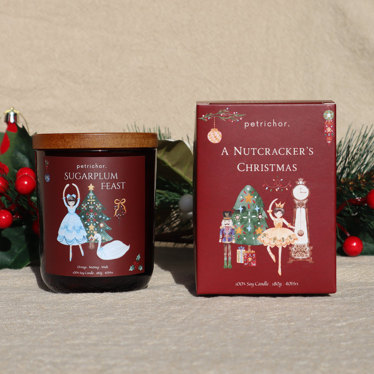 Sugarplum Feast Christmas soy candle in a burgundy jar beside its A Nutcracker's Christmas gift box