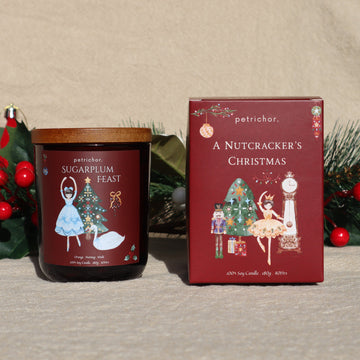 Sugarplum Feast Christmas soy candle in a burgundy jar beside its A Nutcracker's Christmas gift box
