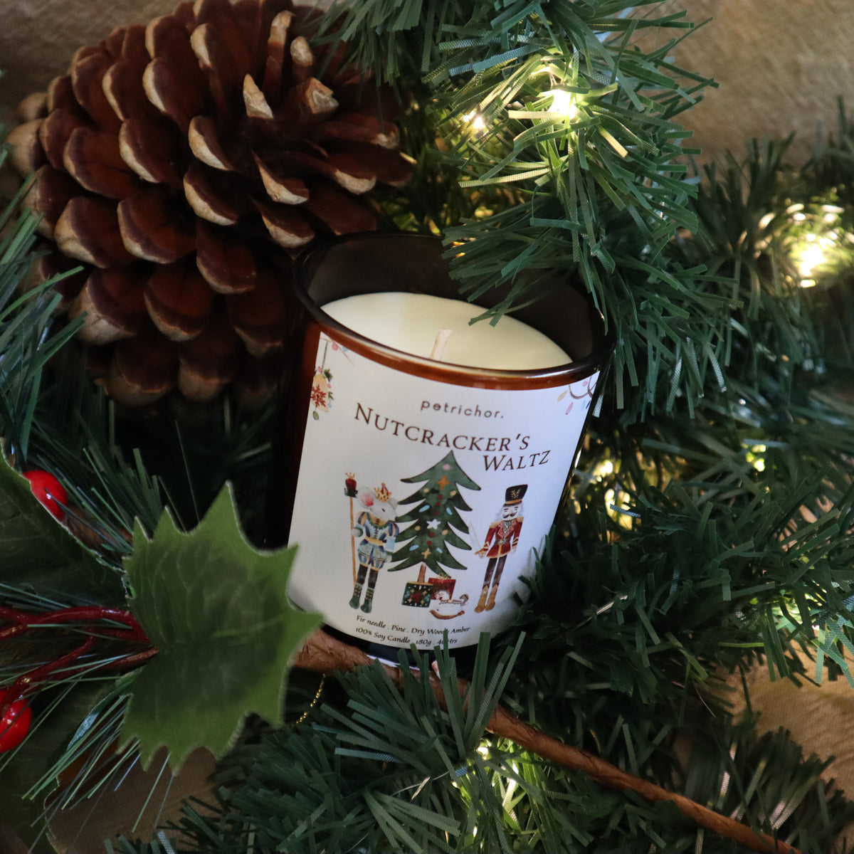 Nutcracker's Waltz Christmas candle among pine branches with a pine cone