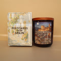 Candle labeled 'Granada Nights' next to a box of 'Postcards from Spain' on a beige background