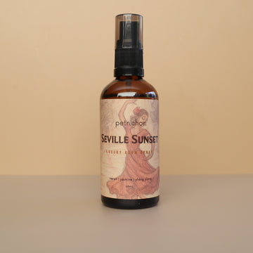 Bottle of Seville Sunset room spray with a decorative label on a beige background