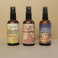Three bottles of petrichor room sprays with different labels on a beige background