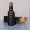 Bottle of petrichor Teak & Neroli Luxury Room Spray on a reflective surface with a neutral background