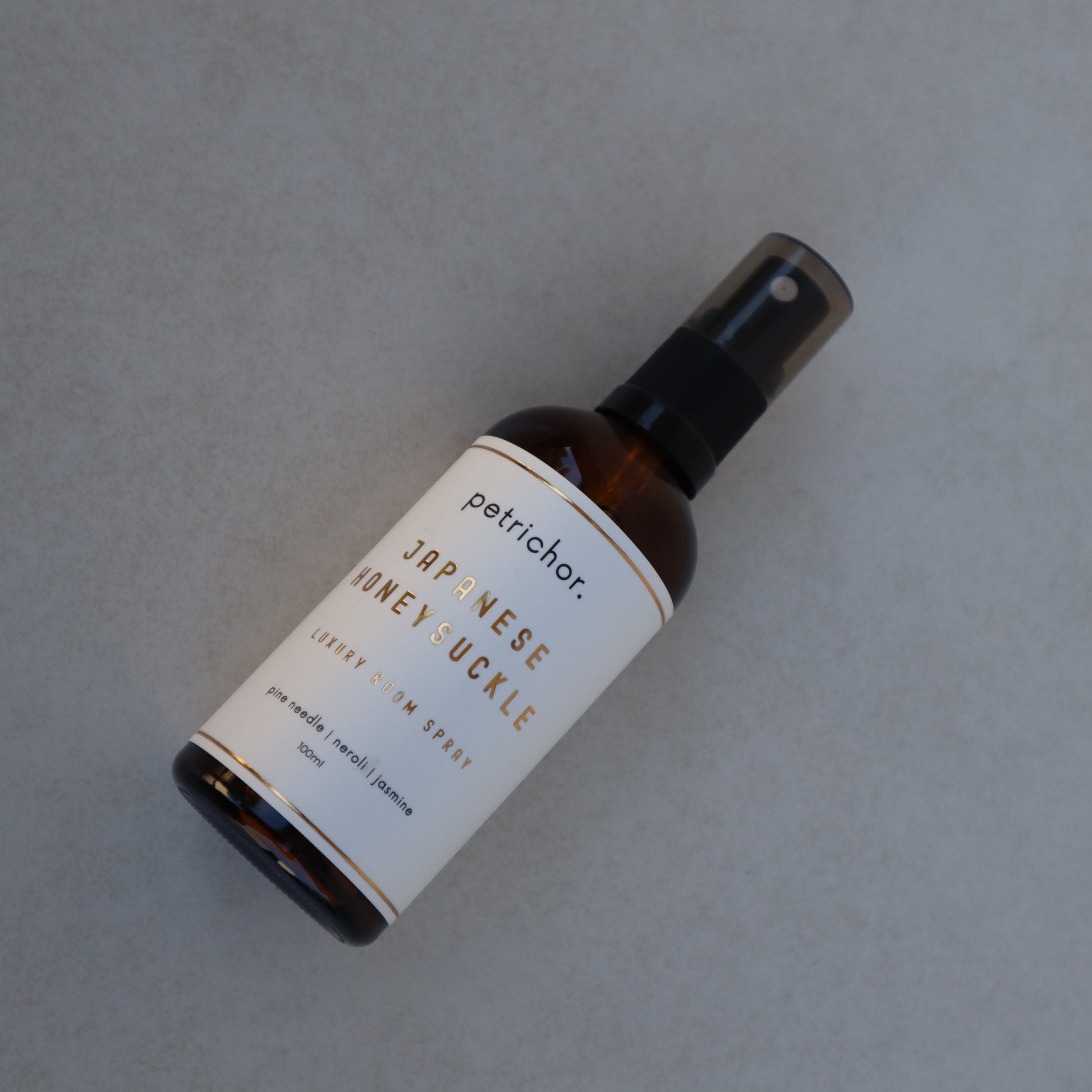 Bottle of petrichor Japanese Honey Luckle spray on a gray background