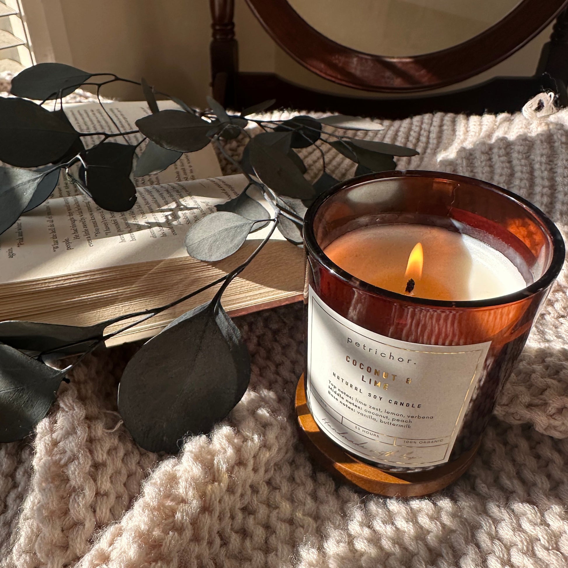 Candle in a decorative holder on a textured surface with leaves