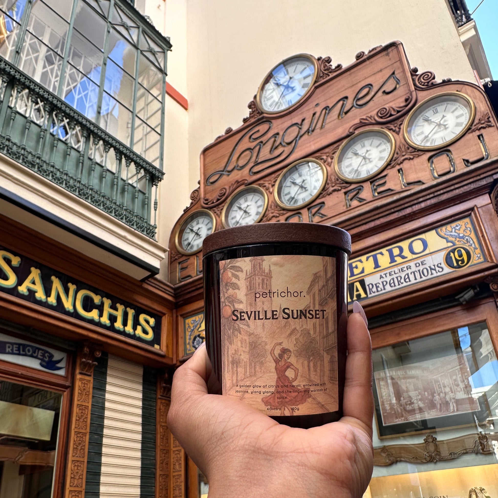 Hand holding a bottle of Seville Sunset rum with decorative background