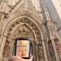 Hand holding a bottle of Seville Sunset wine against an architectural background