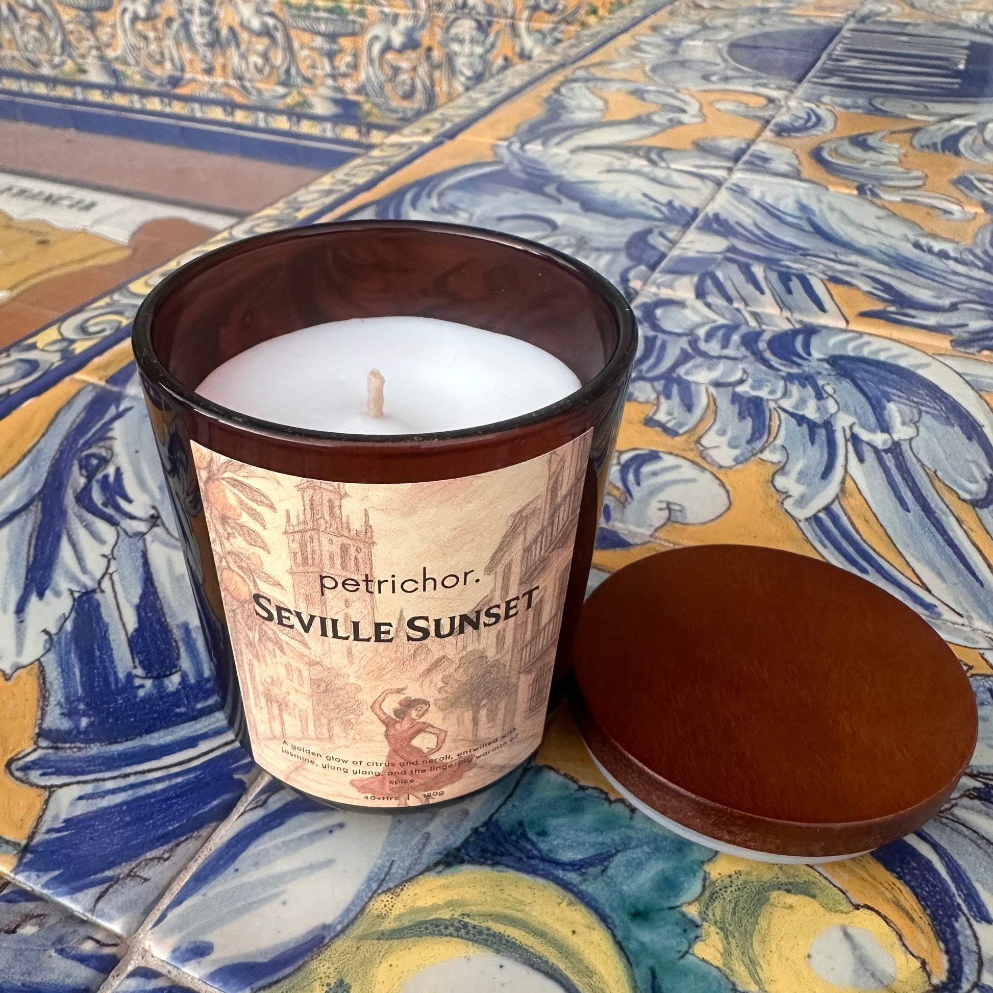 Candle in a decorative container on a colorful tile background