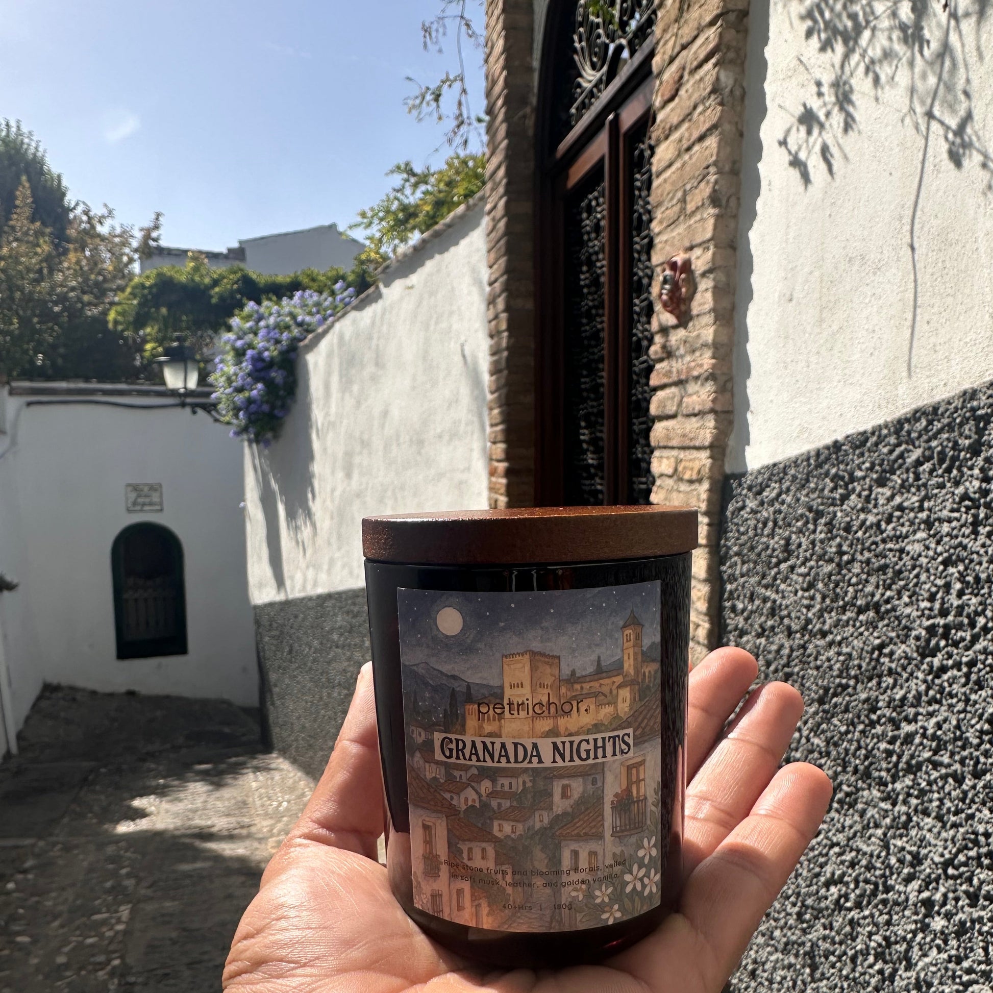 Hand holding a candle, with a street scene in the background.