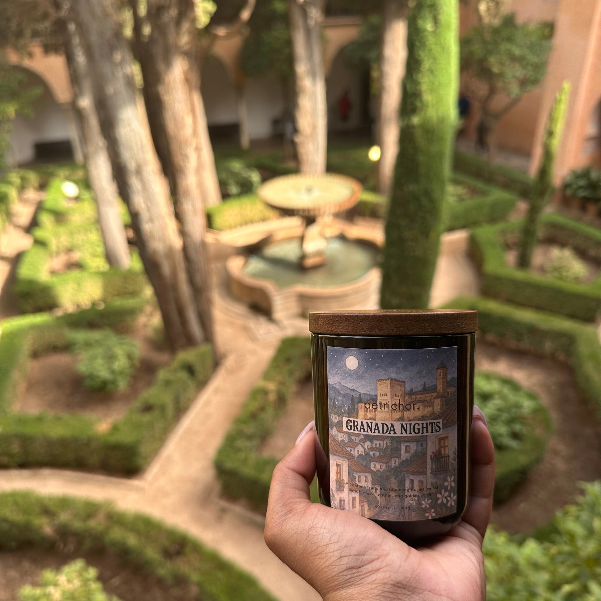 Hand holding a candle, blurred green garden background