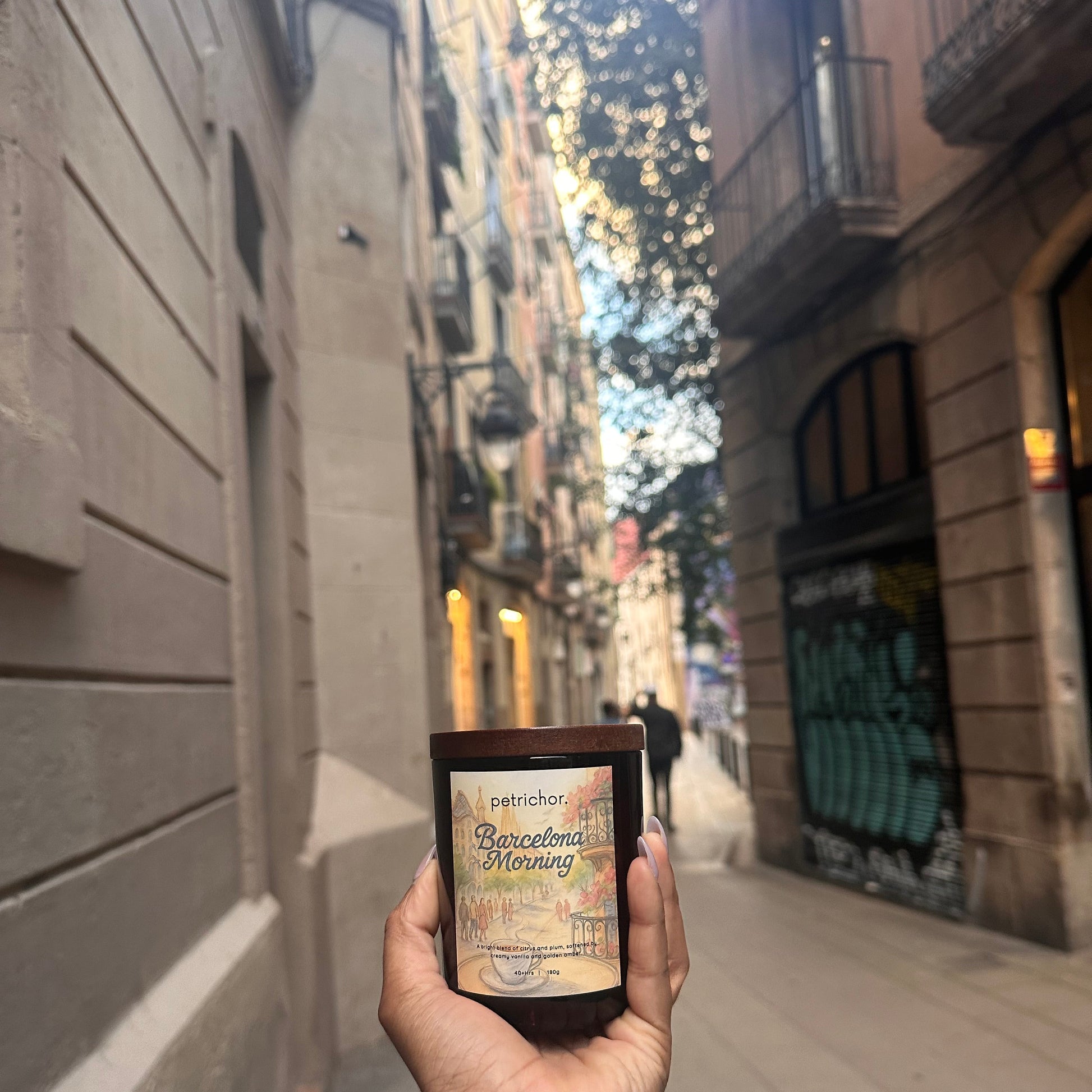 Hand holding Barcelona Morning Candle with a cityscape in the background