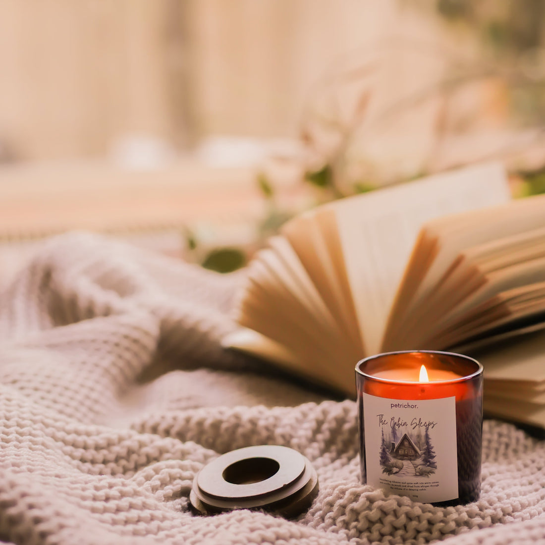 Candle with a label featuring a cabin design on a beige background