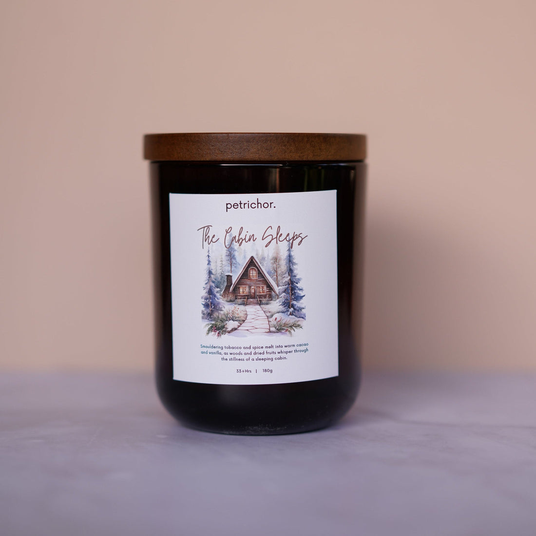 Candle with a label featuring a cabin design on a beige background