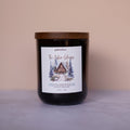 Candle with a label featuring a cabin design on a beige background