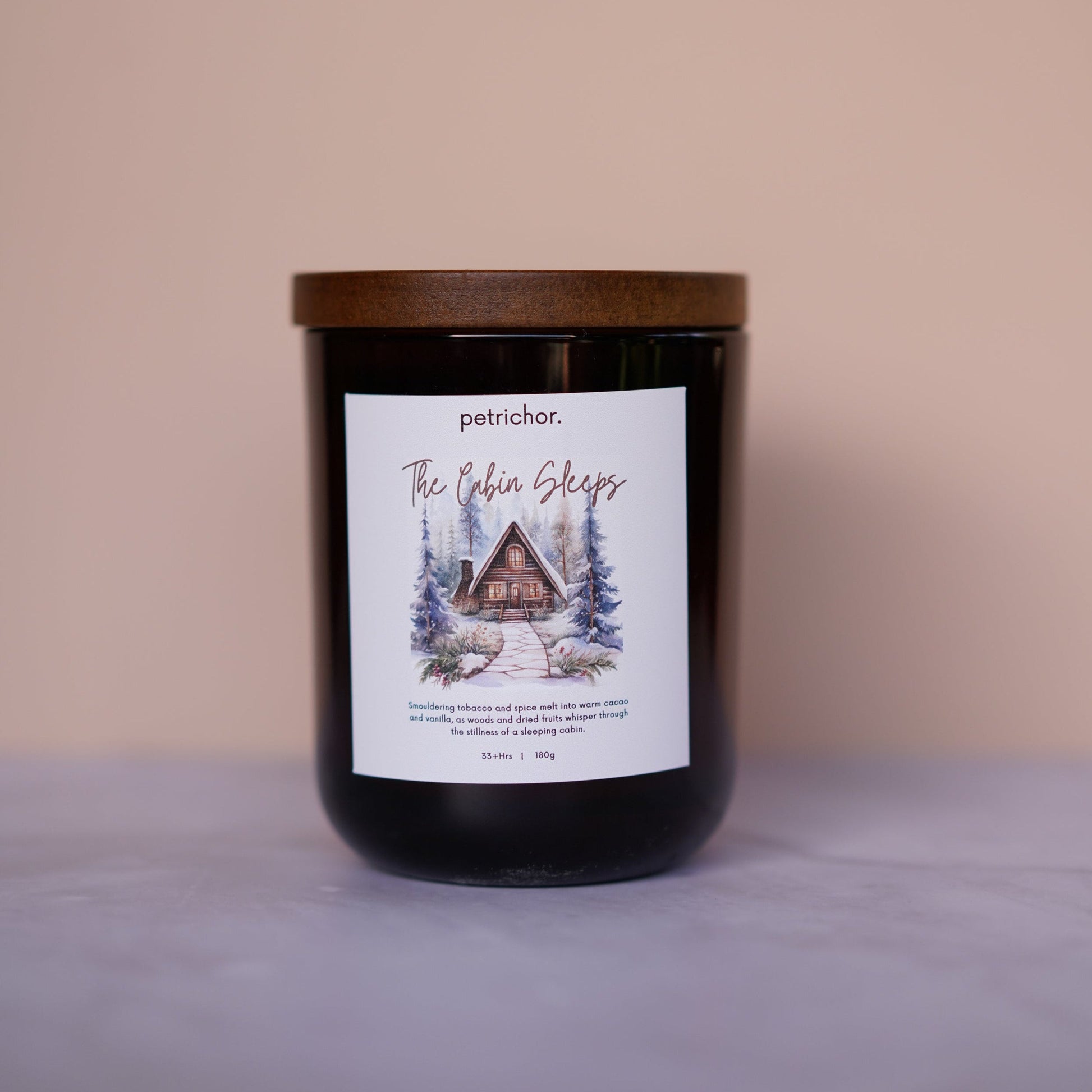Candle with a label featuring a cabin design on a beige background